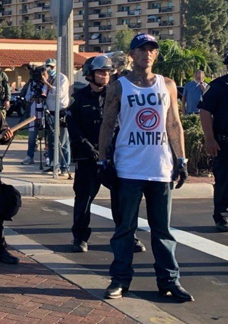 A Defend East County member with a machete who has been at several protests in the region stands in front of police in clear violation of the order banning knives. Photo by Tom Mann.