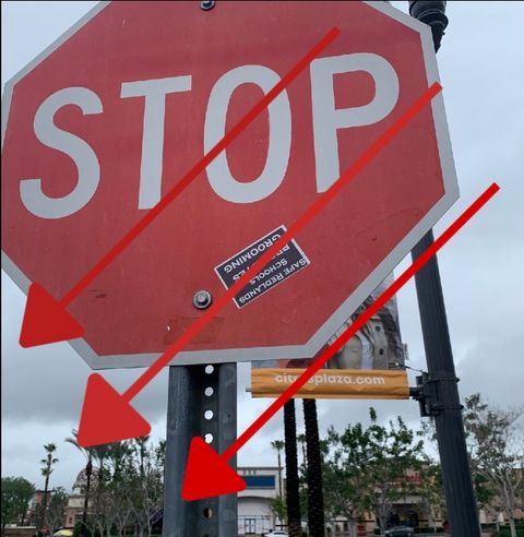A stop sign with an upside down sticker that says "safe redlands schools protects grooming"