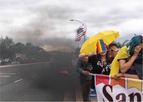pride marchers, one holding a flag over their face, getting blasted by exhaust from a passing pickup truck