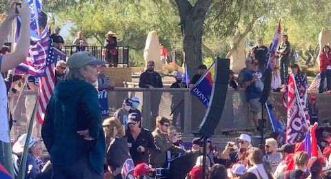 White nationalist Nick Fuentes podium stand at a large Stop the Steal rally near the Arizona Capitol. The crowd is filled with a mixture of Trump and American flags and well known Groypers like Baked Alaska. Jacob Chansley walks away from the podium.