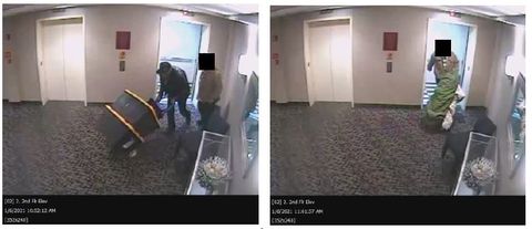 Two men manhandle large heavy boxes and bags through a carpeted hotel lobby into an elevator