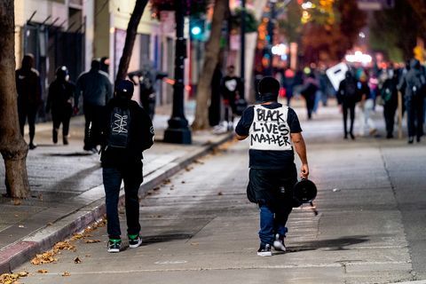 Protesters, one wearing a ballistic vest with 'Black Lives Matter' written on it, walk down Broadway Avenue during the 'Justice for Jacob' protest in Oakland, Calif., August 26, 2020.
