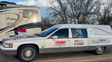A photo of a hearse driven by a convoy attendee, on the back side of the vehicle it says “collecting democrat votes one dead stiff at a time.” This refers to a conspiracy theory that Democrats are stuffing ballot boxes by registering dead people to vote. The photo on the left is when they first arrived at the ranch, and the photo on the right is after they had been directed to a nearby rest area to tape it up. covering up the word "dead" on the phrase "collecting democrat votes one dead stiff at a time"