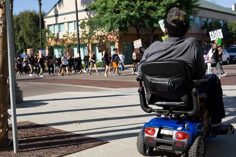 A Black USMC Veteran watches the march from his mobility scooter. Photo by Tom Mann.