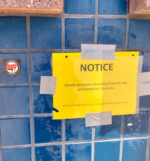 A copy of the city's firearms ban posted in the plaza on July 19, alongside an antifascist action sticker. Photo by Bella Davis.