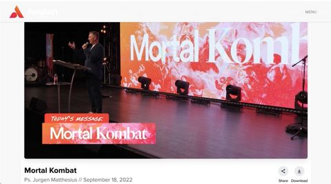 Jurgen Matthesius preaching on a big lit stage with the words "mortal kombat" on a screen behind him. A chiron says "today's message: mortal kombat"