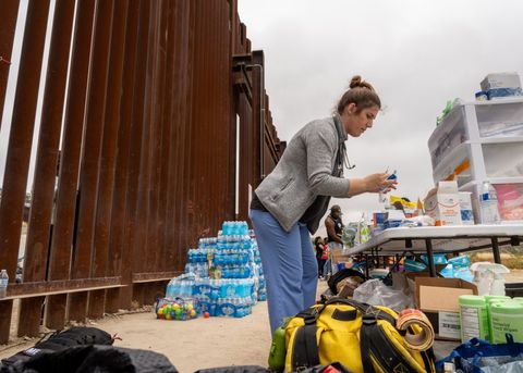 an activist prepares medicine to hand through the border fence