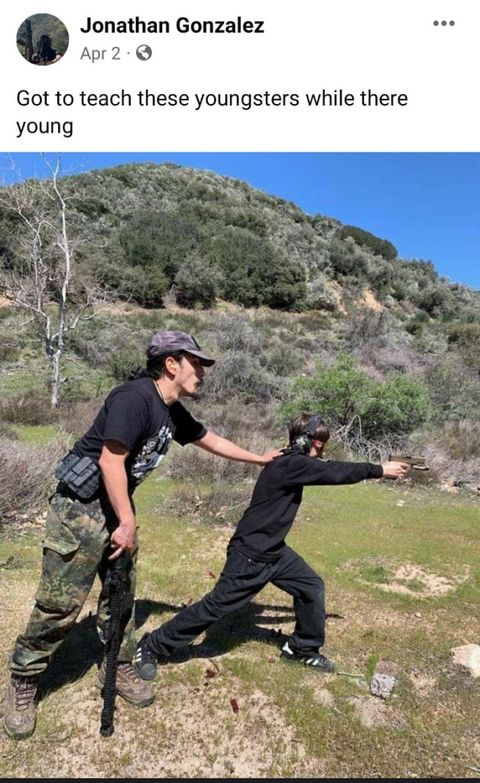 Photo from Jonathan Gonzalez's facebook where he has one hand holding a long gun and the other hand on a child's back as the child shoots a handgun