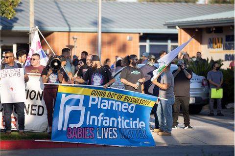 people gathering around a banner that says going out of business soon planned infanticide baby lives matter