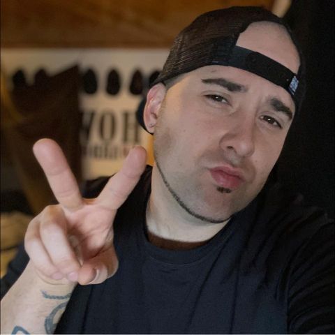 Felix is depicted with a backwards snap-back hat, a tiny soul patch, a closely trimmed neck beard, and pursed lips. Felix is tilting his head somewhat to present a 3/4 view to the camera. He is making a peace sign, but he is tilting it toward the camera somewhat.