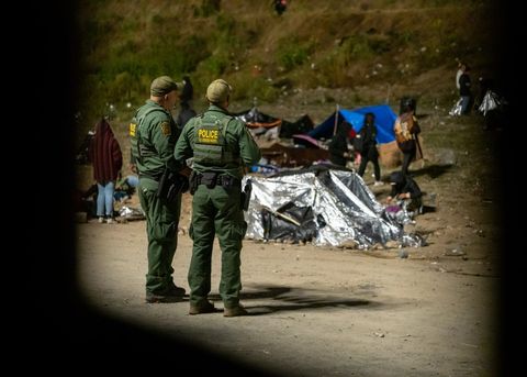 two border agents look at a makeshift camp
