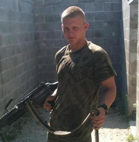 A man posing with a belt-fed light machine gun holding the bullet belt.