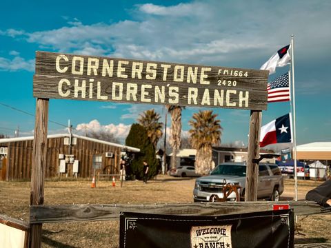 the sign at cornerstone children's ranch with a texas flag american flag and flag with a cross on it 