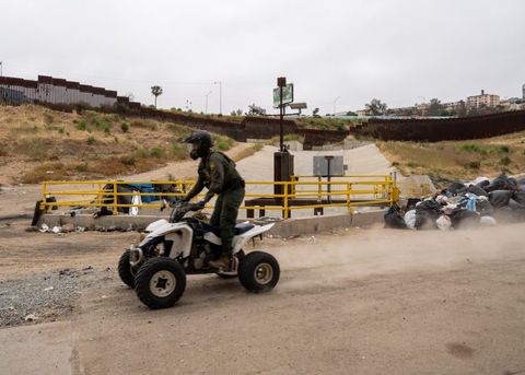 a border patrol agent on a four wheeler atv driving by a camp