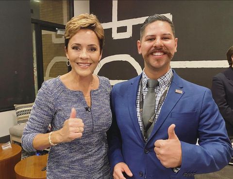 Arizona gubernatorial candidate Kari Lake poses for a photo with fascist videographer Tomas Morales in the Republicans for National Renewal conference room. Both give a thumbs up