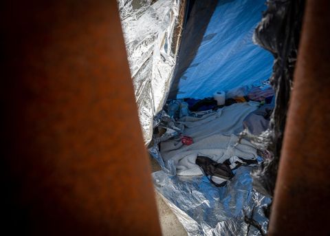 the inside of a tent through the border fence. there's toilet paper on the floor and a shoe.