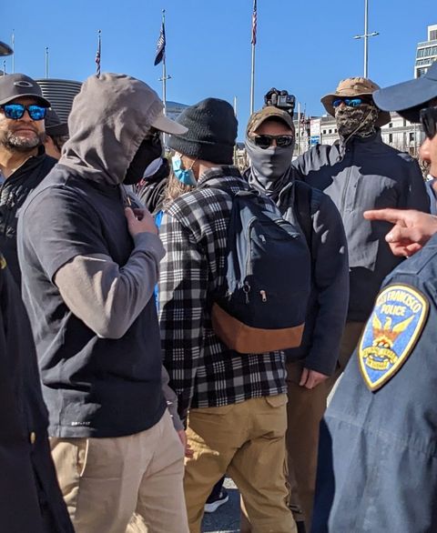 officers conversing with and pointed at masked nazis in a crowded downtown San Francisco