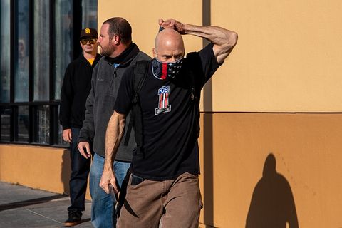 Neo-Nazi who brandished a knife straightens his gaiter and walks toward antifascist counter-protestors. 