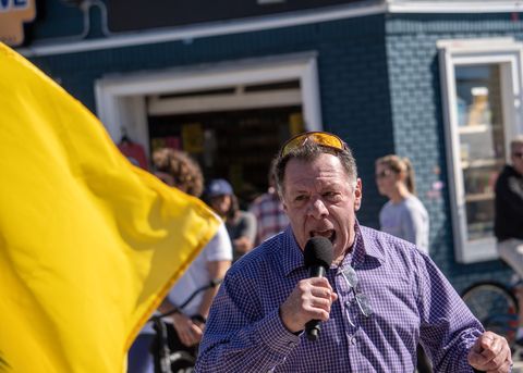 The unidentified speaker yells into a microphone while a gadsden flag blows into frame.N