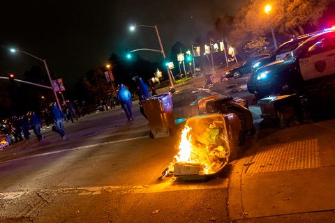 A trash can and its contents burn while police remove blockades from the road during their dispersal of people at the 'Justice for Jacob' protest in Oakland, Calif., August 26, 2020.