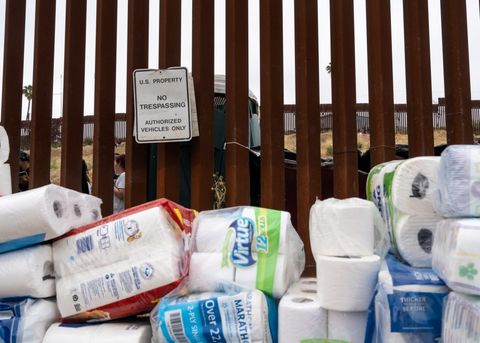 toilet paper and paper towels stacked near the border fence