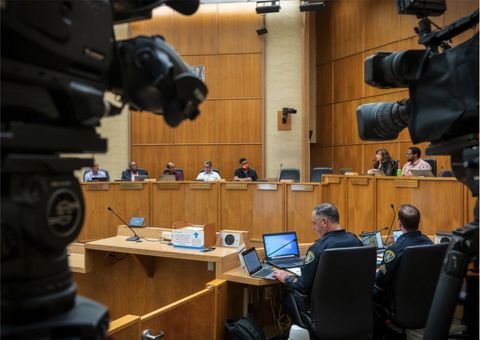 SDPD made its initial presentation to the PAB on April 27th, 2023. Two SDPD officers sit in the presentation area just below PAB, whose members are seated at the high desks. Two TV cameras obscure either side of the frame.