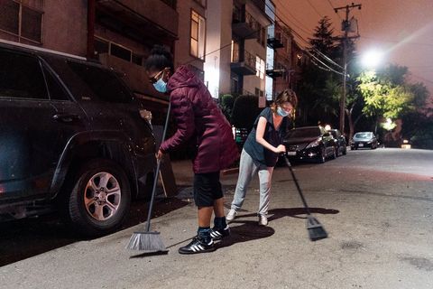 Neighbors of Adams Point sweep their street of glass and other debris left by protesters as they were dispersed by police during the 'Justice for Jacob' protest in Oakland, Calif., August 26, 2020.