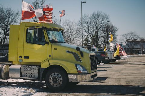 a yellow semi parked with polish and american flags decorating it