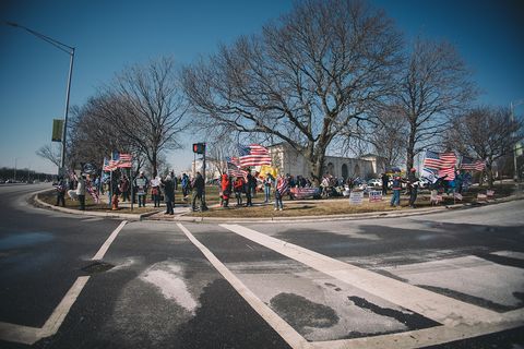 a group of forty or so people standing on a street corner waving flags