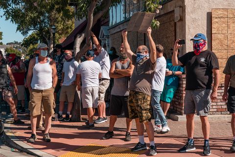 A group of counter-protesters watches as several hundred march from the Contra Costa County Courthouse to the Waterfront Park in Martinez, Calif., on Sunday, July 12, 2020.