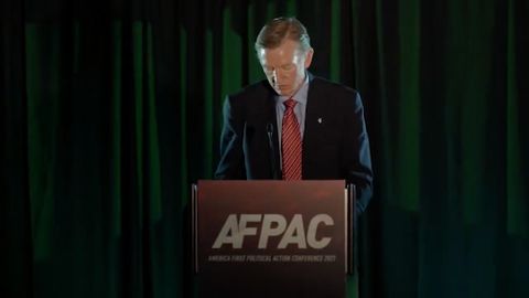 Rep. Paul Gosar stands at a podium giving a speech at AFPAC II. The sign on the podium reads 'AFPAC: America First Political Action Conference 2021'