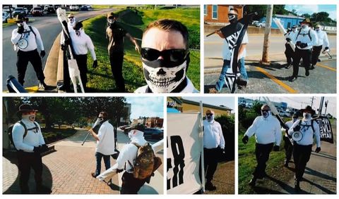 A series of images showing five men, two of whom are wearing jeans, tee-shirts and skull masks and three of whom are wearing identical uniforms of white long-sleeve shirts, black pants, black boots and white gaiter-style masks branded with the OMTO logo. The men are walking down various streets, carrying large banners and flying flags that read: “White Lives Matter”.