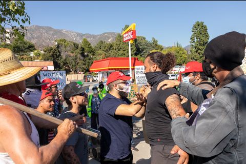 Right-wingers push a protester in front as his arms are extended, blocking those behind him.